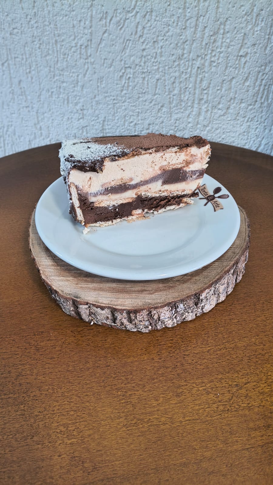 Fatia de torta trufada de bolacha, com camadas de bolacha, creme e chocolate, finalizada com açúcar de confeiteiro